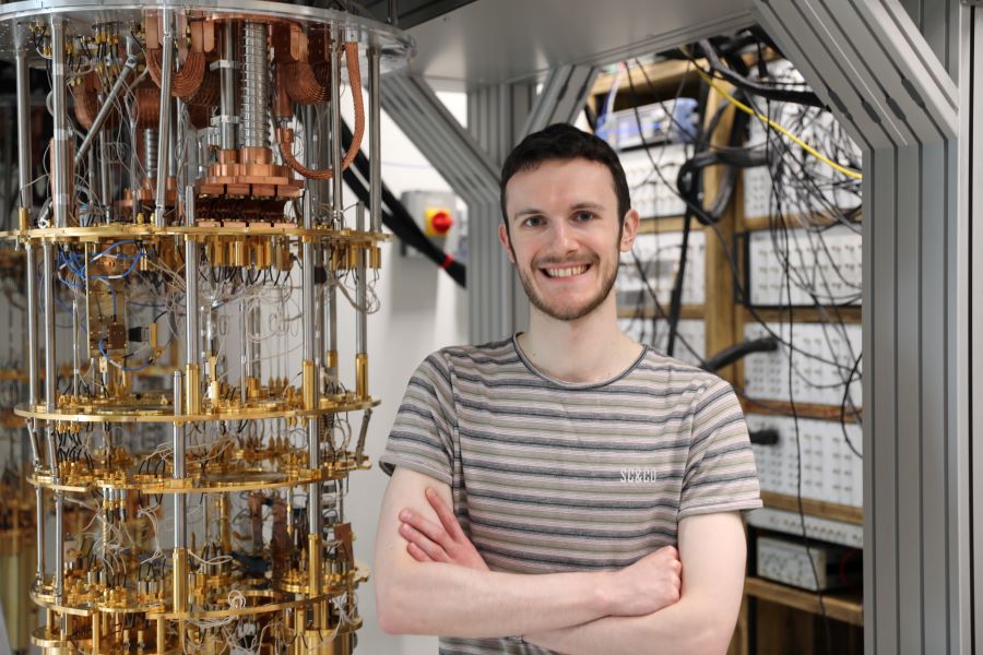 An image of Edward Thomas in a lab next to a dilution refrigerator